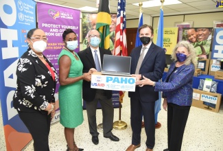 Minister of State in the Ministry of Health and Wellness, Hon. Juliet Cuthbert-Flynn (second left), receives 10 laptop computers and other devices for the National Vaccination Programme from representatives of the Pan American Health Organization/World Health Organization, and United States Agency for International Development (USAID), at PAHO offices in St. Andrew, on Monday  (April 11). Others pictured (from left) are Advisor to PAHO, Dr. Marion Bullock DuCasse; PAHO Representative to Jamaica, Ian Stein; Country Representative (Ag) at USAID Jamaica, Alex Gainer, and Health Team Lead at USAID, Wendy Benzerga.