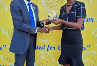 Principal of the Jonathan Grant High School in Spanish Town, St. Catherine, Dr. O’Neil Ankle (left), presents the Principal’s Award – Form Teacher of the Term – to teacher at the school, Krisan Thomas, on May 2.