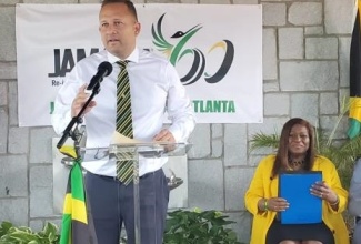 Jamaica’s Consul-General in Miami, Oliver Mair, delivering the message from Minister of Culture, Gender, Entertainment and Sport, Hon. Olivia Grange, at the Atlanta launch of Jamaica-60 celebration activities. Seated is Jamaica’s honorary consul in Atlanta, Dr. Elaine Bryan.

