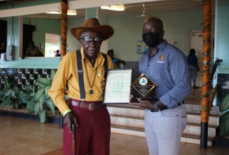 The Minister of Agriculture and Fisheries, Hon. Pearnel Charles Jr (right), presents special appreciation award to Farmer, Maple Gladstone Lawrence, for over 50 years of dedicated service to the Jamaica Agricultural Society (JAS) Branch in St Ann during the eighth staging of the St. Ann Agricultural Industrial and Food Show at Port Rhoades Sport Club in Discovery Bay, St. Ann, on Thursday (May 26).