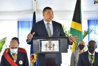 Prime Minister, the Most Hon. Andrew Holness, addresses a ceremony for the installation for the new Custos Rotulorum for St. Andrew, Hon. Ian Forbes, held at the Hope Royal Botanical Gardens in St. Andrew on Thursday (May 12). Listening are Governor-General, His Excellency the Most Hon. Sir Patrick Allen (seated left) and Custos Forbes (seated right).

