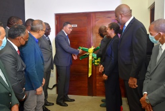 Prime Minister the Most Hon. Andrew Holness (seventh left), cuts the ribbon to officially open the $580 million Jamaica Fire Brigade (JFB) Area 4 Headquarters in Montego Bay, St James. situated at #1 Barnett Street. Assisting him is Minister of Local Government and Rural Development Hon. Desmond McKenzie (fourth right). Sharing the moment are Deputy Prime Minister and Minister of National Security, Hon. Dr. Horace Chang (third left. foreground); Minister of Legal and Constitutional Affairs Marlene Malahoo Forte (third right); and dignitaries from the Jamaica Social Investment Fund (JSIF) and Jamaica Fire Brigade (JFB).