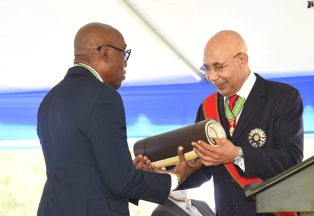 Governor-General His Excellency the Most Hon. Sir Patrick Allen (right), presents newly installed Custos Rotulorum for St. Andrew Hon. Ian Forbes with the Magistrates’ Roll for the parish, during his installation ceremony . The event was held at the Hope Royal Botanical Gardens in the parish on Thursday (May 12).  