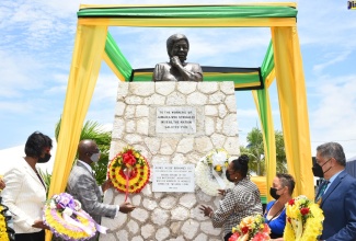 Minister of Local Government and Rural Development, Hon. Desmond McKenzie (second left) and Minister of Culture, Gender, Entertainment and Sport, Hon. Olivia Grange (third right), place wreaths at the Aggie Bernard monument, Kingston Craft Market, downtown Kingston, on May 18, in recognition of National Workers Week/Labour Day. Others looking on are (from left), Chief Technical Director, Ministry of Labour and Social Security, Dione Jennings; Goddaughter of Agnes Bernard, Cordelia Forbes; and President of the Jamaica Employers’ Federation, David Wan. A bust, mounted atop the monument, was unveiled at the event.