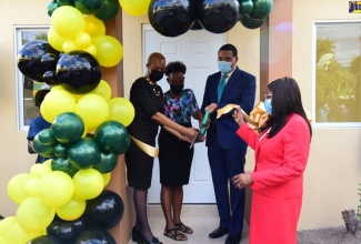 Prime Minister, the Most Hon. Andrew Holness (second right), cuts the ribbon at the handover of a two-bedroom unit under the Government’s New Social Housing Programme (NSHP), in Hermitage, St. Andrew, on May 6. Also taking part (from left) are Member of Parliament for St. Andrew Eastern, Hon. Fayval Williams; beneficiary of the unit, Johana Paul, and Permanent Secretary in the Office of the Prime Minister, Audrey Sewell.