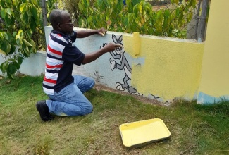 Chairman of the Kitson Town Civic Committee and veteran journalist, Garfield Angus, paints a section of wall at the Kitson Town Basic School in St. Catherine. The Labour Day (May 23) project was organised by the committee through a donation of paint and  equipment from Sherwin-Williams valued at some $90,000.

