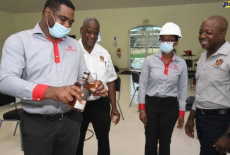 Agriculture and Fisheries Minister, Hon. Pearnel Charles Jnr (right), observes as National Rums of Jamaica Limited Group Operations Manager, Michael Dunkley (left), pours a product sample during a visit to Clarendon Distillers Limited on Friday (May 27). Also looking on are State Minister in the Ministry of Agriculture, Hon. Franklin Witter (second left); and Chief Executive Officer, National Rums of Jamaica, Martha Miller.