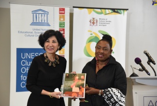 Director and Representative, UNESCO Cluster Office for the Caribbean, Dr. Saadia Sanchez-Vegas, symbolically hands over the 300-page ‘Reshaping Policies for Creativity Global Report’ held at the AC Hotel in New Kingston on Thursday (May 19).