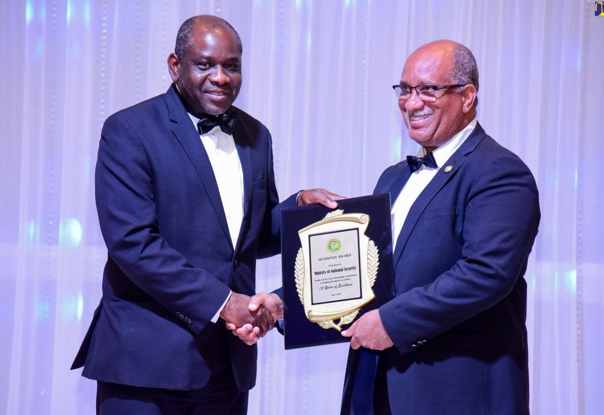 Permanent Secretary in the Ministry of National Security, Courtney Williams (left), accepts a diamond award from Chief Executive Officer, Passport, Immigration and Citizenship Agency (PICA), Andrew Wynter, for the Ministry’s outstanding contribution in helping the agency to achieve 15 years of excellence, during the PICA stakeholders’ banquet at the AC Hotel by Marriott Kingston, on June 23.