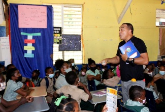 Minister of Health and Wellness, Dr. the Hon. Christopher Tufton (standing), engages with students at the Paul’s Mountain Primary School in St. Catherine, during a recent wellness forum at the institution.

