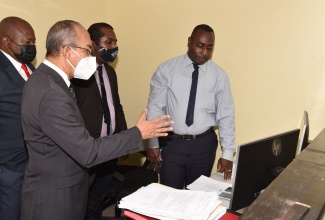 Minister of National Security, Hon Dr. Horace Chang (left), makes an observation of the new the Multi-Biometric Identification System, during his visit to the Jamaica Constabulary Force’s Criminal Records Office on Thursday (June 9). Looking on are (from left) Head of the JCF Technology Branch, Assistant Commissioner of Police, Leonardo Brown; Detective Sergeant Kirkland Tomlinson, and Detective Corporal Logan Thomas.  