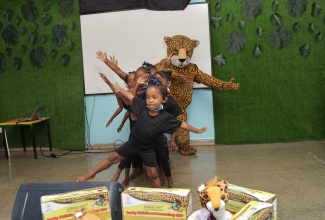 Students at the Union Gardens Infant School and Teacher, Ms. Nyoka McKoy, dressed as a mascot, perform an item at the launch of the 'Little Jamaican Early Childhood Learning Kit' held recently, at the Union Gardens Infant School in Kingston.