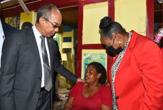 Deputy Prime Minister and National Security Minister, the Hon. Dr. Horace Chang (left) and Culture, Gender, Entertainment and Sport Minister, Hon. Olivia Grange (right) attempt to console bereaved mother and grandmother, Gwendolyn McKnight whose family was killed in the community of Chapelton, Clarendon in the early hours of Tuesday (June 21) morning. The victims have been identified as mother of four, 31 year old Kemisha Wright and her children: Kimana Smith (age 15), Shemari Smith (age 10), Kafana Smith (age 5), and Kishaun Henry (23 months old). The Government officials went to the community on Tuesday to visit family members and loved ones of the victims. 