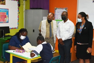 Chairman of the Jamaica Education Transformation Commission (JETC), Professor Orlando Patterson (standing left), observes as Literacy Teacher at Tivoli Gardens High School, Keisha Ebanks (seated left), guides a student in a reading session. Looking on (standing from left) are Principal of the school, Marvin Johnson and Regional Director for Kingston and St. Andrew, Ministry of Education and Youth, Dasmine Kennedy. Professor Patterson visited the school in Kingston on Thursday (June 2), to gather feedback on recommendations made in the JETC report that was published on January 13, 2022. 