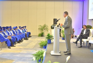 Prime Minister, the Most Hon. Andrew Holness (at podium), addresses the graduation ceremony for the first batch of coders  from the Amber HEART Academy, at the AC Hotel by Marriot Kingston, recently. At right is Founder and Chief Executive Officer of the Amber Group, Dushyant Savadia.

