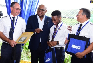 Minister of Tourism, Hon. Edmund Bartlett (second from left), presents gifts to the InterCaribbean Airways flight crew, who brought the first scheduled international flight into the Ian Fleming International Airport in Boscobel, St Mary, on Thursday (June 16). From left is Captain Ciro Chacon; flight attendant, Joshua Christiano Small; and Pilot, Peter Stanley.


