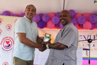 Health and Wellness Minister, Dr. the Hon. Christopher Tufton (left) presents Psychiatric Nursing Aide at the Bellevue Hospital, Anthony Phillips, with the ‘Outstanding Team Partnership Award’ in recognition of his contributions to the sector, during the institution’s Staff Wellness Day and Awards Ceremony on Wednesday (June 20). The event forms part of activities for National Healthcare Workers Appreciation Month (July) and was held at the Hospital’s Windward Road location in St. Andrew. The Bellevue Hospital is mandated to provide psychiatric and rehabilitative care for the mentally ill.  