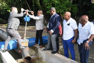 Minister without Portfolio in the Ministry of Economic Growth and Job Creation, Senator the Hon. Matthew Samuda (left), is assisted by Member of Parliament (MP) for St. Mary South East, Dr. the Hon. Norman Dunn (second left), to turn on the improved Iterboreale well pump in St. Mary on July 21. Observing (from third left) are: National Water Commission’s (NWC) Regional Manager, Richard Williams; His Worship the Mayor of Port Maria, Richard Creary and MP for St. Mary Central, Dr. Morais Guy.  