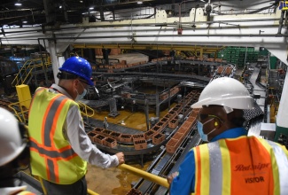 Minister of Industry, Investment and Commerce, Senator the Hon. Aubyn Hill (right), and Red Stripe’s Managing Director, Luis Prata, view one of several production lines, during a tour of the company’s plant on Spanish Town Road in Kingston, on Tuesday (July 26).