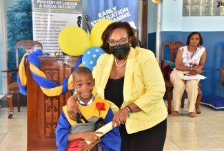 Chief Technical Director, Ministry of Labour and Social Security, Audrey Deer-Williams, presents a certificate and school bag to graduate Dominic Thomas, during the Early Stimulation Programme (ESP) graduation ceremony, held at the Apostolic Church of Jamaica Bethel Temple, 6-8 Central Avenue, Kingston Gardens, on July 20.