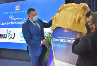 Prime Minister the Most Hon. Andrew Holness (left) and Chief Technical Director, Office of the Cabinet, Marjorie Johnson unveil the Service Excellence Policy during the official launch at the Office of the Prime Minister in St. Andrew on July 13.