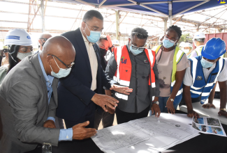 Prime Minister, the Most Hon. Andrew Holness (second left) discusses plans for the Morant Bay Urban Centre project with, from left, Mayor of Morant Bay, Councillor Michael Hue; Architect, Bryan Morris; Kencasa Project Management group representative, Claire-Ann Kennedy; and Chairman of the Factories Corporation of Jamaica (FCJ), Lyttleton Shirley. The Prime Minister toured the site on Thursday (July 14) where he observed preparation work underway on the project.