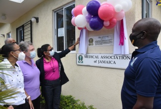 Chief Medical Officer, Ministry of Health and Wellness, Dr. Jacquiline Bisasor-McKenzie (third left), officially unveils a commemorative plaque to honour front-line healthcare workers in the national COVID-19 pandemic response, which has been mounted at the Medical Association of Jamaica (MAJ) office on Windsor Avenue in Kinston, during a recent ceremony. Also participating in the event (from left) are Jamaica Medical Doctors Association (JMDA) President, Dr. Mindi Fitz Henley; Chair, Healthcare Workers Appreciation Month National Planning Committee, the Most Hon. Professor Denise Eldemire Shearer; and MAJ President, Dr. Brian James.