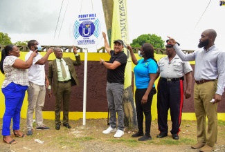 Chief Executive Officer of the Universal Service Fund (USF), Daniel Dawes (third left), and Member of Parliament for St. Catherine West Central, Dr. the Hon. Christopher Tufton (fourth left), lead in celebrating the establishment of a free secured Wi-Fi hotspot in the community of Point Hill, in the parish, on August 4. Others (from left) are Vice President of the Point Hill Community Development Committee, Anna-Kim Williams; Field Supervisor with the Social Development Commission (SDC), Jeremy Jones; Community Development Officer with the SDC, Shaunette Flemming; Corporal Dennis Williams, and Guidance Counsellor at the Point Hill Primary School, Feliciano Thorpe.