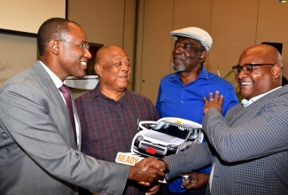 Minister of Finance and the Public Service, Dr. the Hon. Nigel Clarke (left), greets Product and Sales Development Manager, LASCO Microfinance Limited, Richard Benjamin (right, during the recent launch of the Development Bank of Jamaica (DBJ) Entertainment and Transport Sector Loans, at the AC Marriott Kingston Hotel. Others (from second left) are Owner/Operator, Blue Diamond Taxicab Company Limited, Milton Chung; and President, All Island United Route Taxi Association, Raymond Bynes.   