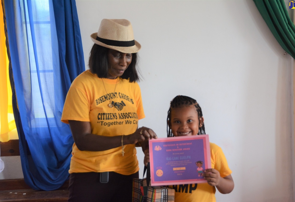 President of the Rosemount Gardens Citizens Association and Deputy Superintendent of Police, Yvonne Whyte-Powell, presents a certificate to summer camp participant, Kai-Lani Guelph, at the graduation ceremony, held at the Rosemount Gardens Moravian Church, Montego Bay, St. James, on August 5.