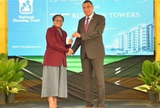 Prime Minister, the Most Hon. Andrew Holness (right), presents new Ruthven Towers homeowner, Paula Brown, with the keys to her apartment, during Wednesday’s (August 3) official opening of the complex, situated at 1-3 Ruthven Road, St. Andrew. The complex was developed by the National Housing Trust (NHT).