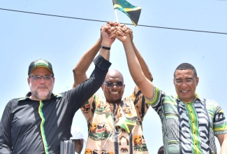 Prime Minister, the Most Hon. Andrew Holness (right), Archbishop of Kingston, Kenneth Richards (centre) and Opposition Leader, Mark Golding (left), raise hands together showcasing unity during the Jamaica 60 Float and Street Parade in Kingston on Monday (August 1).  