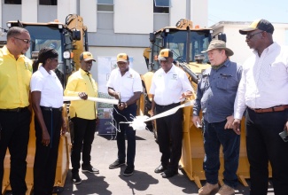 Minister of Agriculture and Fisheries, Hon. Pearnel Charles Jr. (centre) and State Minister, Hon. Franklin Witter (fifth left), participate in a ribbon-cutting exercise at the handover ceremony for two backhoes to the Rural Agricultural Development Authority (RADA) to support farming communities in St. Thomas and Westmoreland. Joining them are (from left) Parish Agricultural Managers, Westmoreland and St Thomas, Yuri Stephenson and Bevene Martin-Dickenson; Acting CEO, RADA, Winston Simpson; Vice Chairman, RADA Board of Directors, Richard King; and Chief Technical Director, Ministry of Agriculture and Fisheries, Orville Palmer.