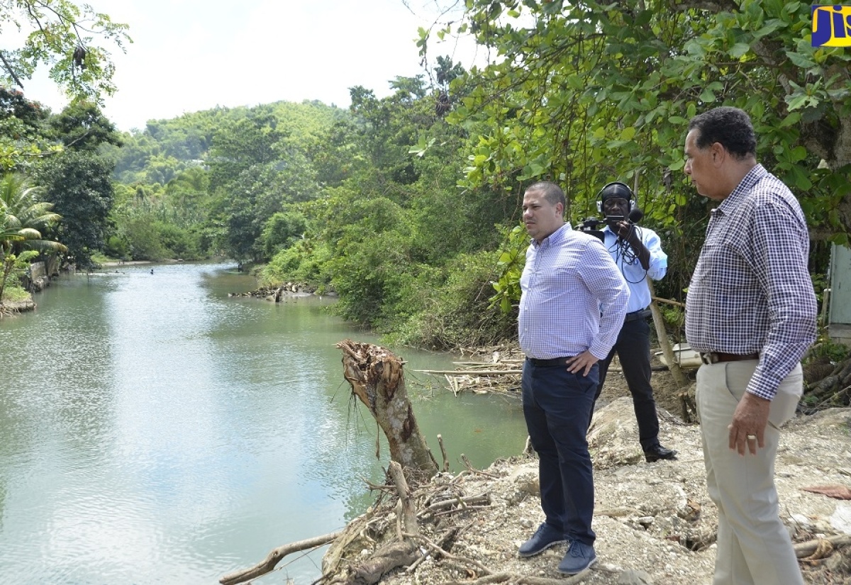 Minister without Portfolio in the Ministry of Economic Growth and Job Creation, Senator the Hon Matthew Samuda (left), and Minister of State in the Office of the Prime Minister (Western Region), Hon. Homer Davis, standing on the Riley River Bridge in Lucea, Hanover, on Thursday (September 8).