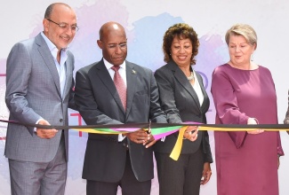 Industry, Investment and Commerce Minister, Senator the Hon. Aubyn Hill (second left), cuts the ribbon to open the New Kingston offices of global outsourcing company Intelcia, on Thursday (September 22). Assisting in the exercise are (from left) Co-Founder and Chief Executive Officer, Intelcia, Karim Bernoussi; President, Jamaica Promotions (JAMPRO), Diane Edwards; and Cluster Director, Caribbean, Intelcia, Mireille De Bruycker.