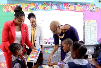 Minister of Education and Youth, Hon. Fayval Williams (right), looks at a book along with several students of the Maverley Primary and Infant School in Kingston during a tour of the institution on Monday (September 5). The institution was one of several in the Corporate Area that Mrs. Williams and other Ministry officials visited to assess the activities on the first day of the 2022/23 academic year. Others (from left) are Assistant Chief Education Officer in charge of the Educational Planning Unit at the Ministry, Dasmine Kennedy; and Acting Chief Education Officer, Dr. Kasan Troupe.  