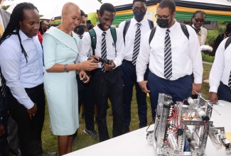 Minister of Education and Youth, Hon. Fayval Williams (second left) and Minister of State in the Ministry of Culture, Gender, Entertainment and Sport, Hon. Alando Terrelonge (left) look on as students from the Jamaica College Robotics Club operate a robot they built. The students are (from left) Delano Reid, Jahleel Hibbert and Michael Woods. They were attending the launch ceremony for the 2022/23 academic year, which was held at Cedar Grove Academy in St. Catherine on Tuesday, September 13. 