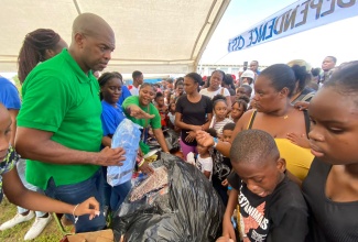 Member of Parliament for St. Catherine Southeast, Robert Miller (left), distribute back to school supplies to patrons at a recent back-to-school treat, held at the Southborough Primary School.