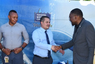 Minister without portfolio in the Ministry of Economic Growth and Job Creation, Senator the Hon. Matthew Samuda (centre), greets Minister without Portfolio with responsibility for Information and Member of Parliament for Clarendon North Central, Hon. Robert Morgan, during the commissioning of the upgraded water system in Wood Hall, Clarendon, on September 8. Looking on is National Water Commission (NWC) Vice President for Operations, Kevin Kerr.