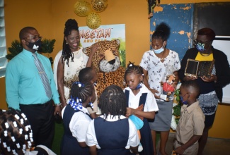 Students gather in the newly renovated media room and library at Ken Wright Primary School in Portland,  to get a closer look at the CHEETAH Mascot, following the official handover of the room during a recent ceremony.  Also sharing the moment are (from left): Education Officer the Ministry of Education and Youth’s Region II, Lebert Drysdale; founder of CHEETAH Toys and More, LLC, Paulette Trowers; Senior Teacher at Ken Wright Primary School, Babara Ferron-Maxwell, and the school’s Principal, Ivorine Bailey-Taylor. 