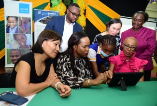 Minister of Education and Youth, Hon. Fayval Williams (seated, right) along with (seated from left) United Nations Children’s Fund (UNICEF) Jamaica Country Representative, Mariko Kagoshima; Acting Chief Education Officer in the Ministry of Education and Youth, Dr. Kasan Troupe and Grade-seven student at St. Hugh’s High School, Shakacia Greenland, view a digital textbook, at the official launch of the Accessible Digital Textbook Prototype in Jamaica on September 30 at the Joyce Robinson Hall, Kingston and St. Andrew Parish Library. Others (standing from left) are Founder and Chief Executive Officer, BookFusion, Dwayne Campbell; Regional Inclusive Education and Disability Specialist, UNICEF, Cynthia Brizuela and Director General, Jamaica Library Service, Maureen Thompson.