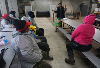 President of the Jamaica Confederation of Trade Unions (JCTU), Helene Davis-Whyte (standing), speaks to a group of women on a Canadian apple farm on Thursday (October 13). Mrs. Davis-White chairs the factfinding team that is probing the status of Jamaican farm workers in Canada.