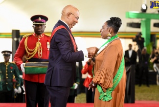 Governor-General, His Excellency, the Most Hon. Sir Patrick Allen (centre) presents Minister of Culture, Gender, Entertainment and Sport, Hon. Olivia Grange, with the Order of Jamaica (OJ) during the 2022 Ceremony of Investiture and Presentation of National Honours and Awards, held at King’s House in Kingston on Monday (October 17). 