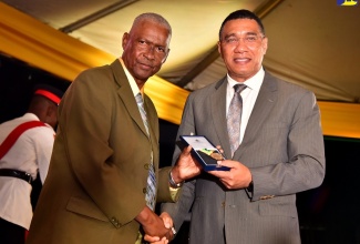 Prime Minister, the Most Hon. Andrew Holness (right), presents retired educator 67-year-old Devon Vassel with the Prime Minister’s Medal of Appreciation for Service to Education, during a ceremony held at Jamaica House, on September 8.