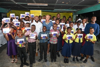 Minister of Education and Youth, Hon. Fayval Williams (centre), with students, members of the Golden Foundation, and teachers in West Kingston, at the handover of 70 tablets to students in West Kingston, recently, at the Denham Town Community Centre.