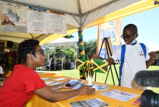 Manager at the Jamaica Information Service (JIS) Montego Bay Regional Office, Tashion Stennett (left), engages grade-six student at Tomlinson’s Christian Academy in Ocho Rios, St. Ann, Giovanni Boswell, during the 24th staging of the Seville Heritage Expo, held at the Seville Heritage Park in St Ann, on Wednesday, October 12.