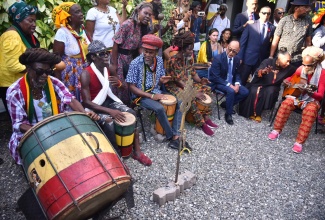 President of the Crown Council of Ethiopia, His Imperial Highness Ermias Selassie (third right, seated), being entertained by drummers while at Culture Yard in Trench Town, on October 18. Minister of Culture, Gender, Entertainment and Sport, Hon. Olivia Grange, is seated at second right.