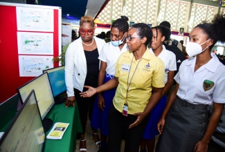 Head of the Geography and Geology Department at the University of the West Indies (UWI), Mona, Dr. Sherene James-Williamson (left). listens as Scientific Officer in the UWI’s Earthquake Unit, Karleen Blake (centre), explains the Geographic Information Systems (GIS) on display, during the 20th GIS Day National Exposition on Wednesday (November 16). The event was hosted by the UWI. Students looking on (from second left) are Shoya-Kay Espeut and Shackera Wray from Buff Bay High School in Portland, and Nailah Allen from Montego Bay High School