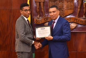 Prime Minister, the Most Hon. Andrew Holness (right), presents Jamaica House Fellowship Programme participant, Christopher Harper, with a certificate during a farewell luncheon on Wednesday (November 2). The luncheon was held at Jamaica House. Mr. Harper was among the seven participants comprising the second cohort of Fellows under the programme.