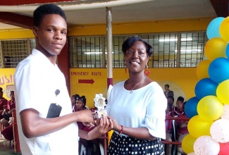 Dean of Discipline at Lennon High School, in Clarendon, Katrice Meeks (right), presents Devon Anderson, with his trophy during a recent ceremony at the institution. The trophy was presented for a good deed done at the school.